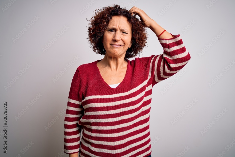 Middle age beautiful curly hair woman wearing casual striped sweater over white background confuse and wonder about question. Uncertain with doubt, thinking with hand on head. Pensive concept.