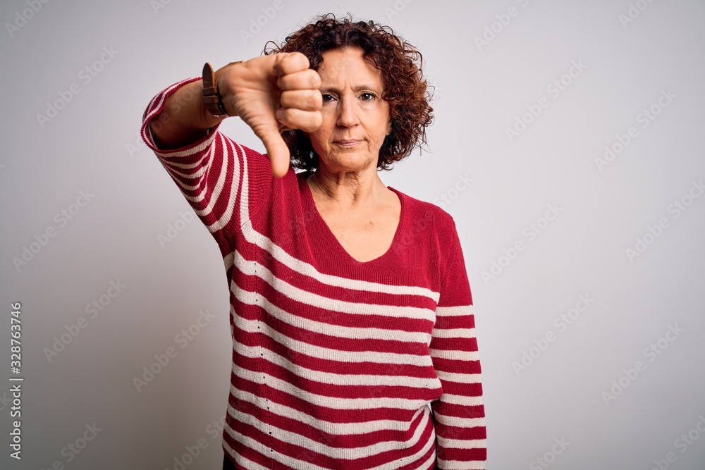 Middle age beautiful curly hair woman wearing casual striped sweater over white background looking unhappy and angry showing rejection and negative with thumbs down gesture. Bad expression.