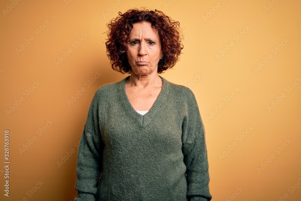 Middle age beautiful curly hair woman wearing casual sweater over isolated yellow background depressed and worry for distress, crying angry and afraid. Sad expression. Middle age beautiful curly hair woman wearing casual sweater over isolated yellow background depressed and worry for distress, crying angry and afraid. Sad expression.