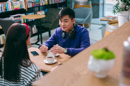 Smiling man listening to lady in cafe stock photo