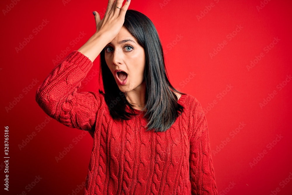 Young brunette woman with blue eyes wearing casual sweater over isolated red background surprised with hand on head for mistake, remember error. Forgot, bad memory concept. Young brunette woman with blue eyes wearing casual sweater over isolated red background surprised with hand on head for mistake, remember error. Forgot, bad memory concept.
