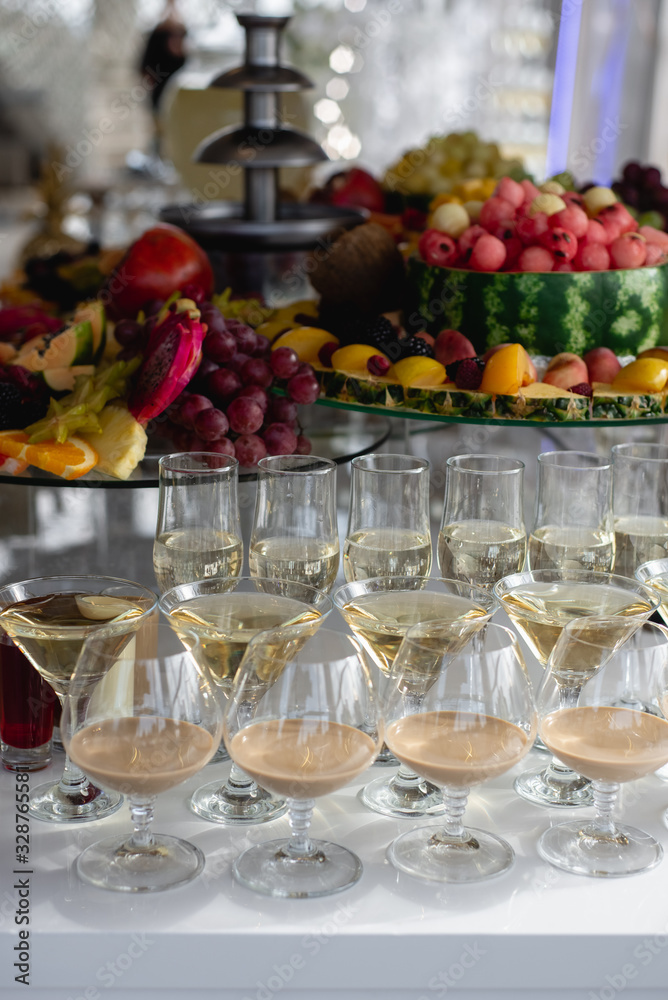 Vertical images of alcoholic cocktails on festive table with watermelon, grape, pitahaya, carambola, banana and different fresh fruits. Celebration or other event