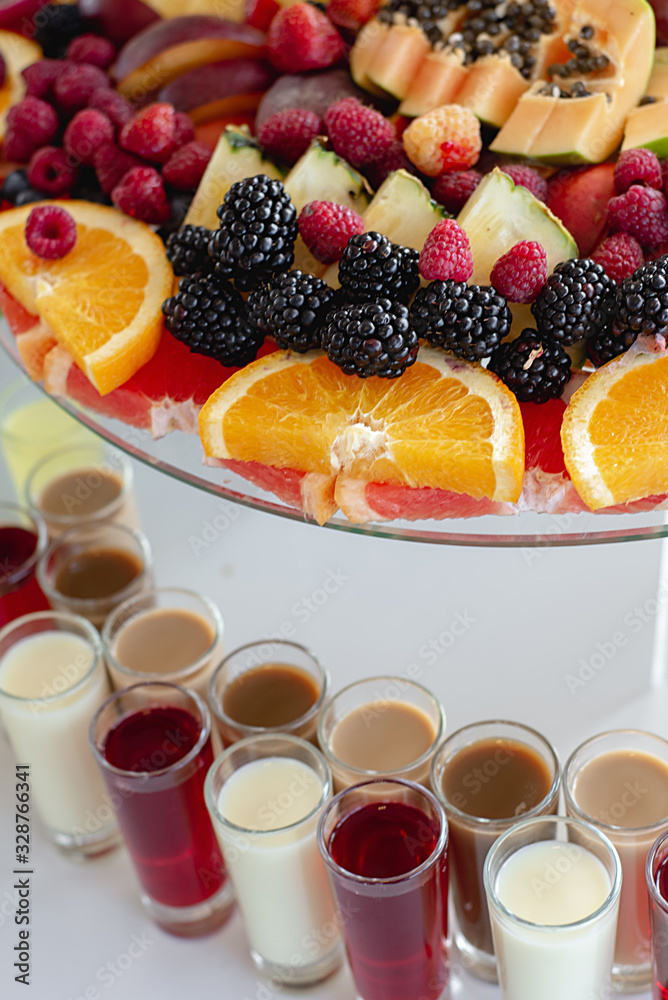 Close up of alcoholic cocktails on festive table with oranges, berries and different fresh fruits. Celebration or other event Close up of alcoholic cocktails on festive table with oranges, berries and different fresh fruits. Celebration or other event