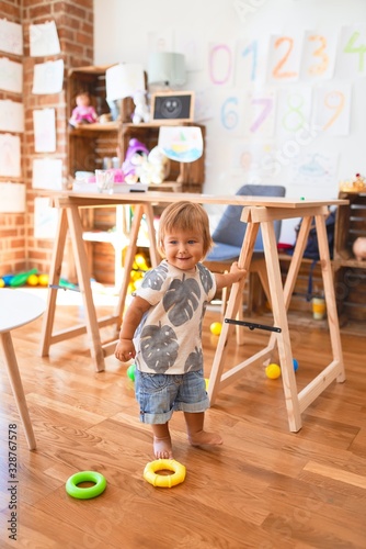 Adorable toddler playing around lots of toys at kindergarten