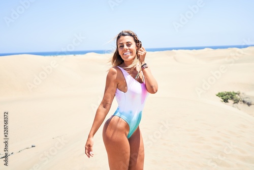 Young beautiful girl on vacation smiling happy and confident. Standing with a smile on face at beach