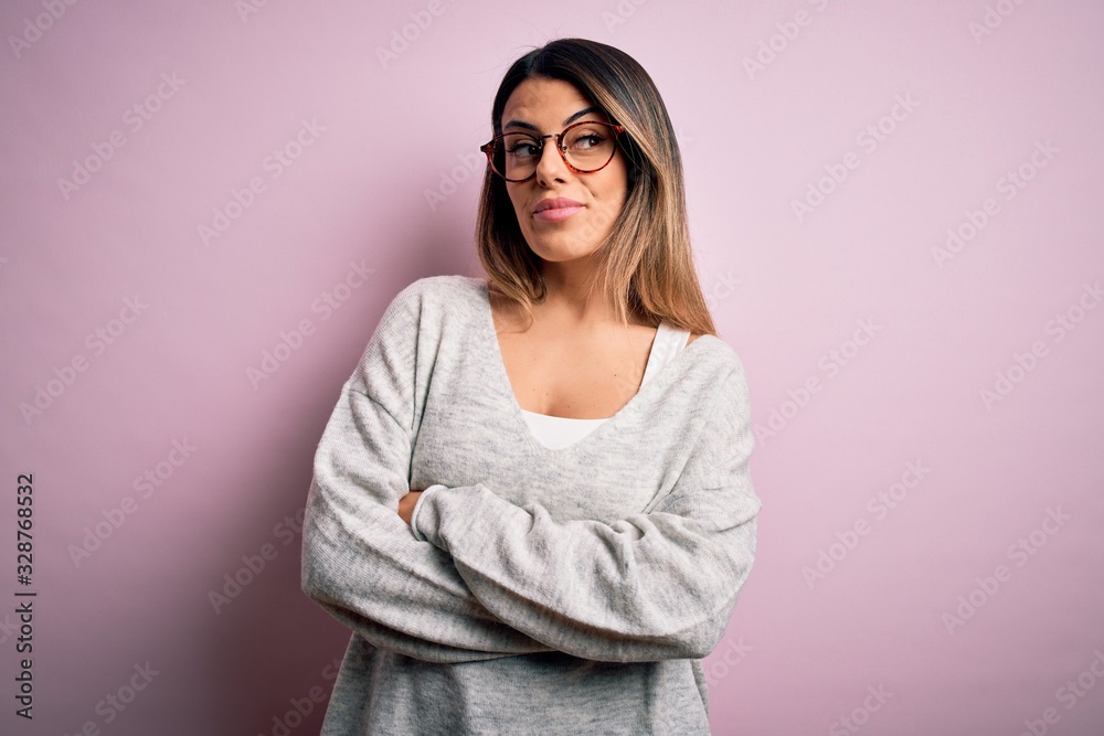 Young beautiful brunette woman wearing casual sweater and glasses over pink background smiling looking to the side and staring away thinking. Young beautiful brunette woman wearing casual sweater and glasses over pink background smiling looking to the side and staring away thinking.