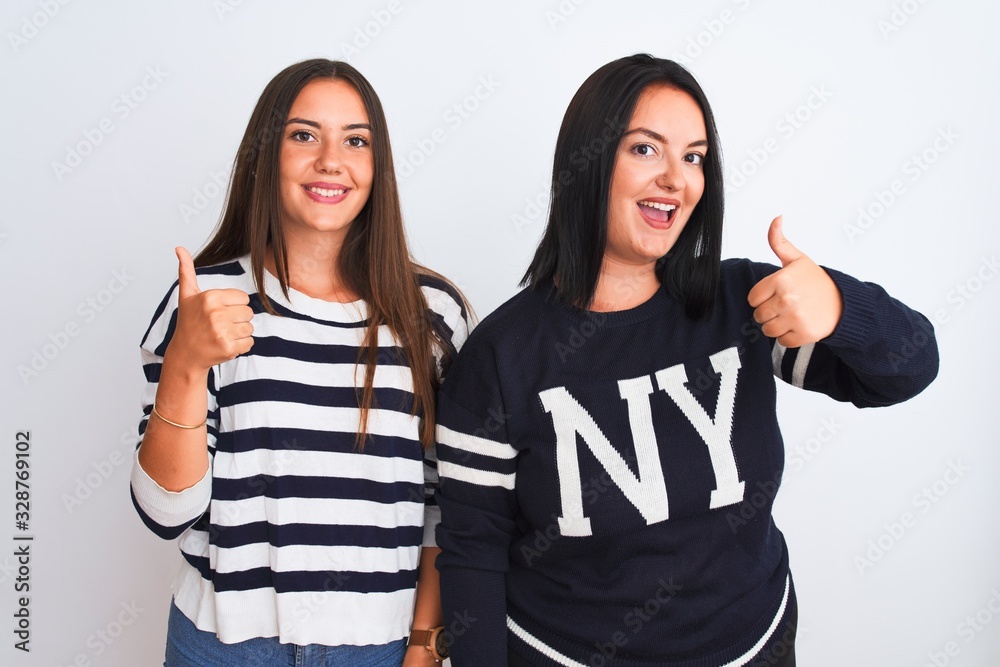 Young beautiful women wearing casual clothes standing over isolated white background doing happy thumbs up gesture with hand. Approving expression looking at the camera showing success. Young beautiful women wearing casual clothes standing over isolated white background doing happy thumbs up gesture with hand. Approving expression looking at the camera showing success.