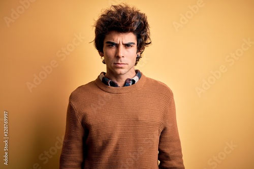 Young handsome man wearing casual shirt and sweater over isolated yellow background skeptic and nervous, frowning upset because of problem. Negative person. © Krakenimages.com