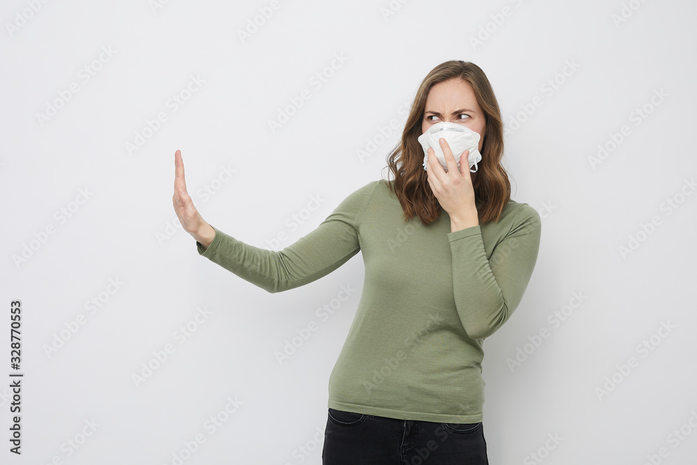 Beautiful woman holding a protective mask to stop the corona virus covid19 pandemic disease saying stop with one hand while protecting herself Beautiful woman holding a protective mask to stop the corona virus covid19 pandemic disease saying stop with one hand while protecting herself