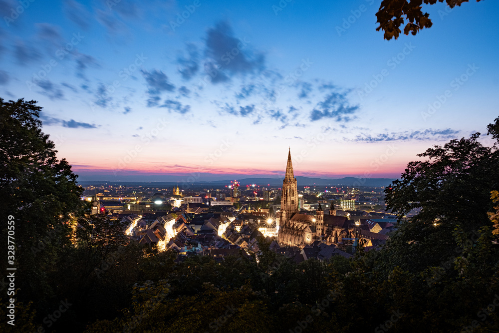 Naklejka premium Panorama der Skyline von Freiburg im Breisgau bei Nacht nach Sonnenuntergang mit rotem Himmel in magischer Dämmerung von oben