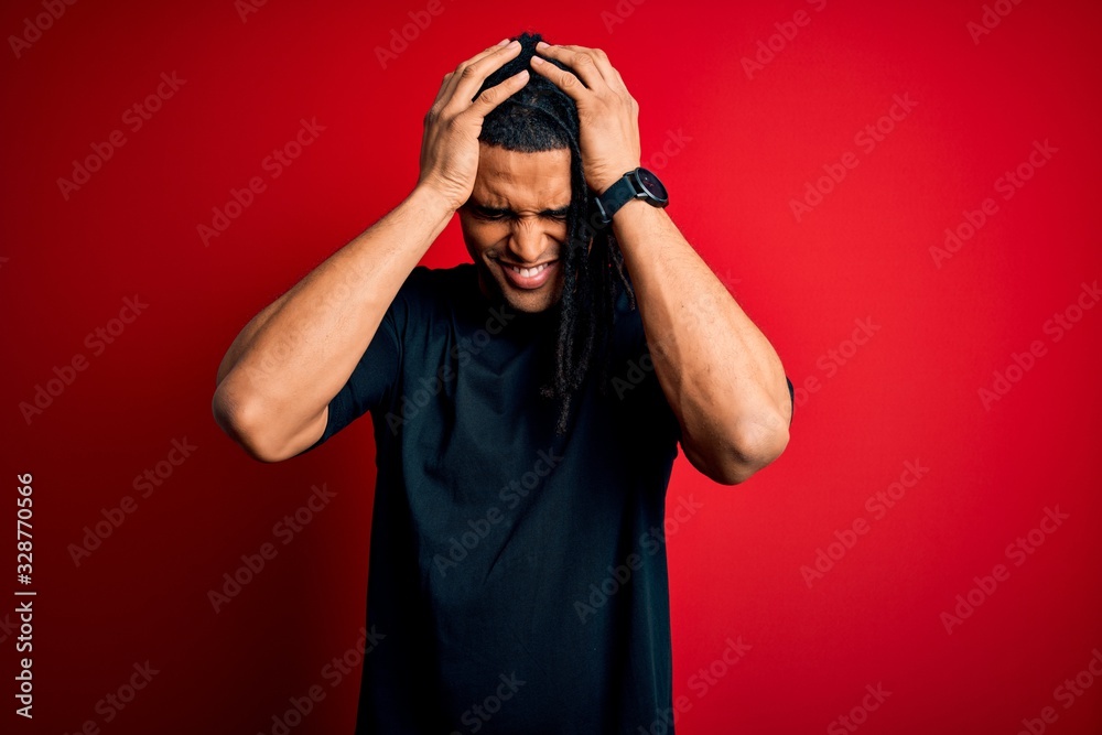 Young handsome african american afro man with dreadlocks wearing casual t-shirt suffering from headache desperate and stressed because pain and migraine. Hands on head. Young handsome african american afro man with dreadlocks wearing casual t-shirt suffering from headache desperate and stressed because pain and migraine. Hands on head.