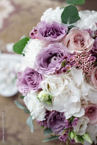 Top view on beautiful modern and stylish wedding bouquet of white, purple roses and eucalyptus greenery. Summer floral composition.