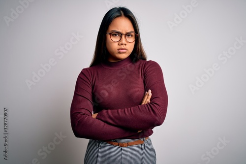 Beautiful asian business woman wearing casual sweater and glasses over white background skeptic and nervous, disapproving expression on face with crossed arms. Negative person. © Krakenimages.com
