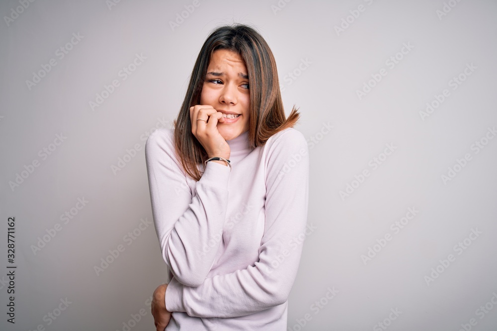 Young beautiful brunette girl wearing casual sweater standing over isolated white background looking stressed and nervous with hands on mouth biting nails. Anxiety problem. Young beautiful brunette girl wearing casual sweater standing over isolated white background looking stressed and nervous with hands on mouth biting nails. Anxiety problem.