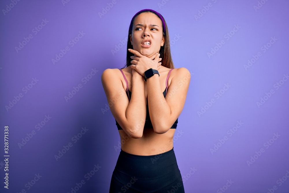 Young beautiful sporty girl doing sport wearing sportswear over isolated purple background shouting suffocate because painful strangle. Health problem. Asphyxiate and suicide concept. Young beautiful sporty girl doing sport wearing sportswear over isolated purple background shouting suffocate because painful strangle. Health problem. Asphyxiate and suicide concept.
