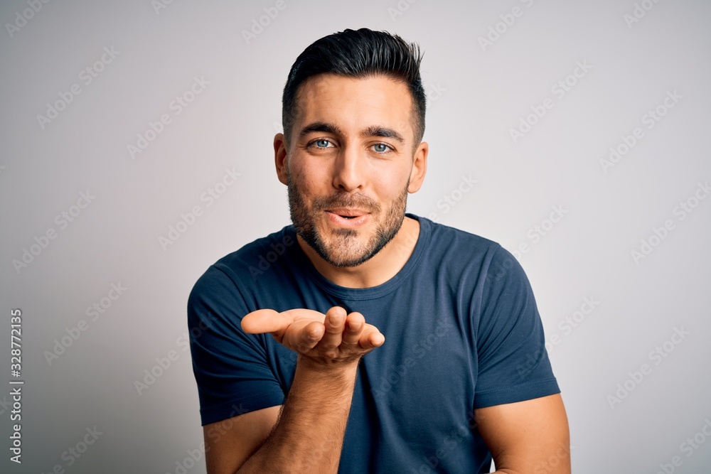 Young handsome man wearing casual t-shirt standing over isolated white background looking at the camera blowing a kiss with hand on air being lovely and sexy. Love expression. Young handsome man wearing casual t-shirt standing over isolated white background looking at the camera blowing a kiss with hand on air being lovely and sexy. Love expression.