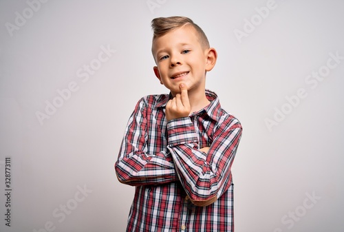 Young little caucasian kid with blue eyes wearing elegant shirt standing over isolated background looking confident at the camera smiling with crossed arms and hand raised on chin. Thinking positive.