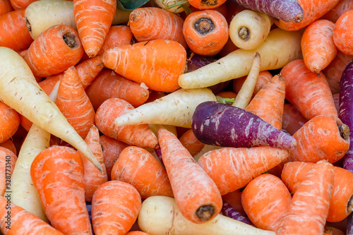 Pile of purple, orange and white Chantenay carrots, Daucus carota, on a market stall. Background image