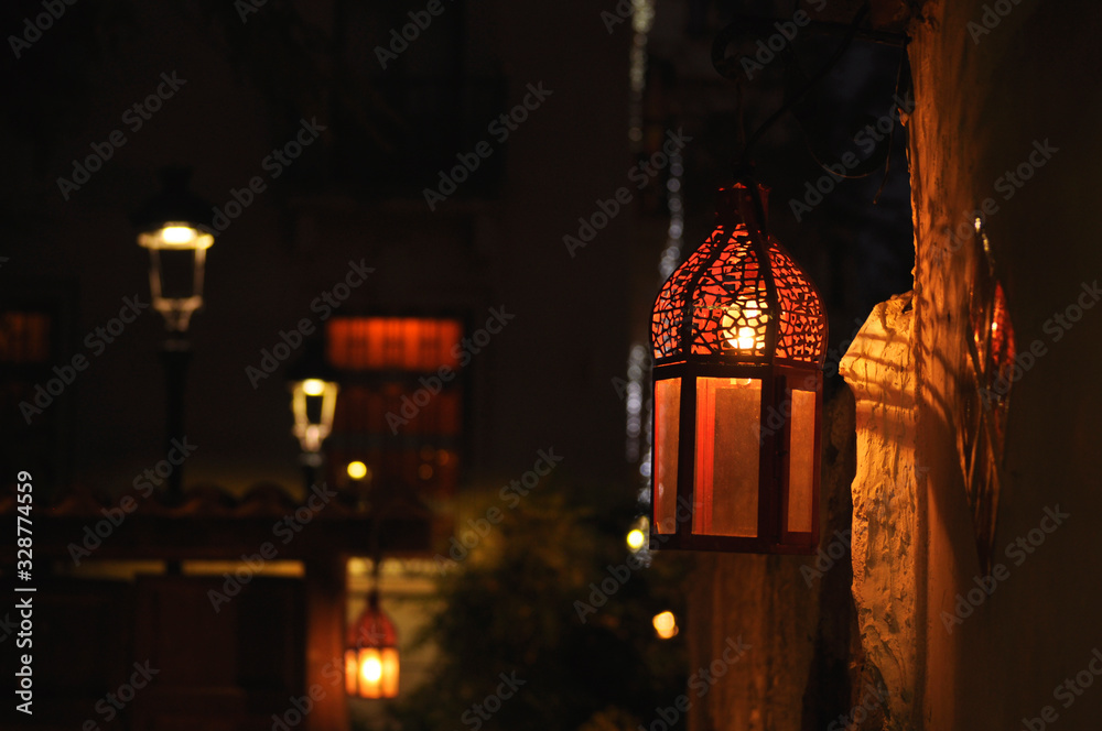 Spanish street lantern hanging on an old wall lighting dimly Spanish street lantern hanging on an old wall lighting dimly