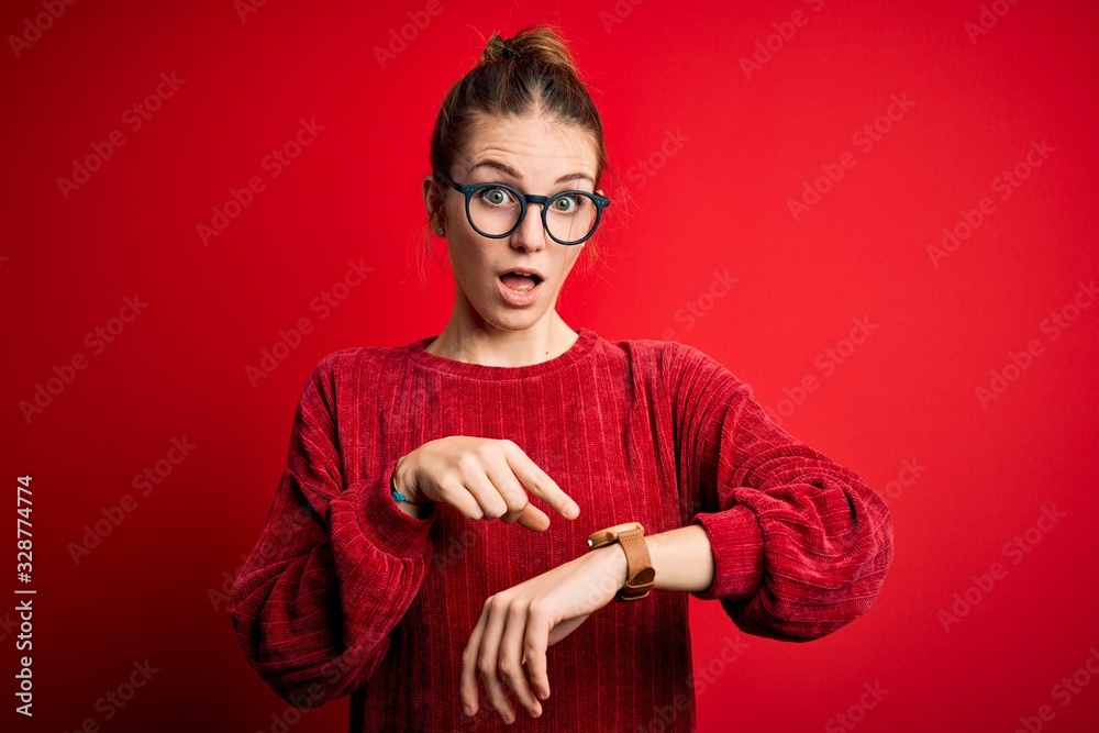 Young beautiful redhead woman wearing casual sweater over isolated red background In hurry pointing to watch time, impatience, upset and angry for deadline delay Young beautiful redhead woman wearing casual sweater over isolated red background In hurry pointing to watch time, impatience, upset and angry for deadline delay