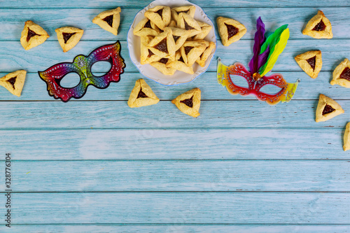 Purim mask and triangle cookies on white background.