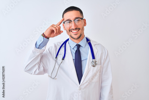 Young doctor man wearing stethoscope over isolated background Smiling pointing to head with one finger, great idea or thought, good memory