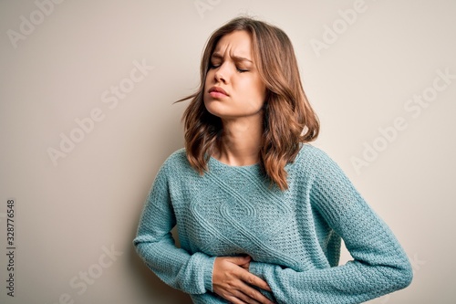 Φωτογραφία Young blonde girl wearing casual blue winter sweater over isolated background with hand on stomach because indigestion, painful illness feeling unwell