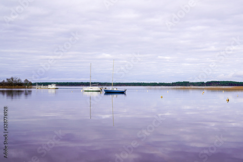 Biscarrosse water boats reflection sky cloud in mirror image in lake landes France