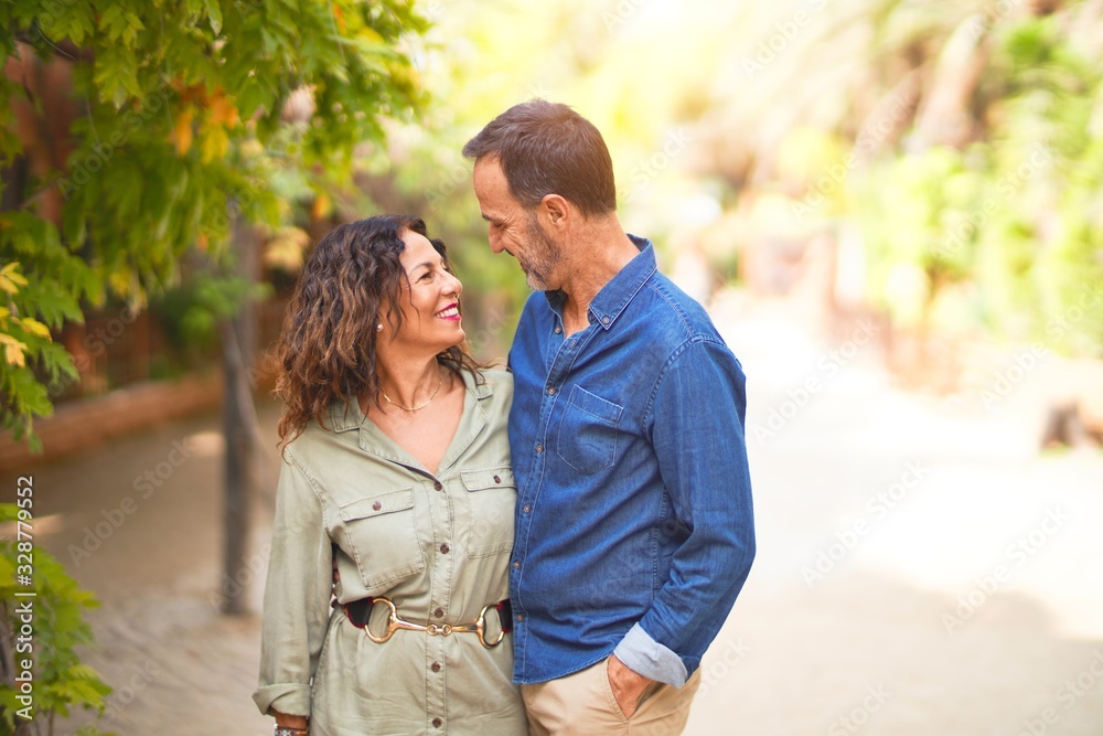 Fototapeta premium Middle age beautiful couple smiling happy and confident at town park. Standing with smile on face and hugging