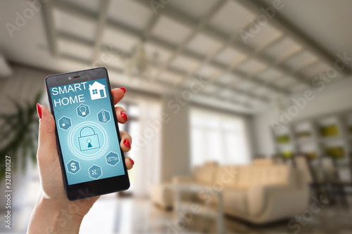 Smart home technology interface on smartphone app screen with augmented reality (AR) view of internet of things (IOT) connected objects in the apartment interior, person holding device