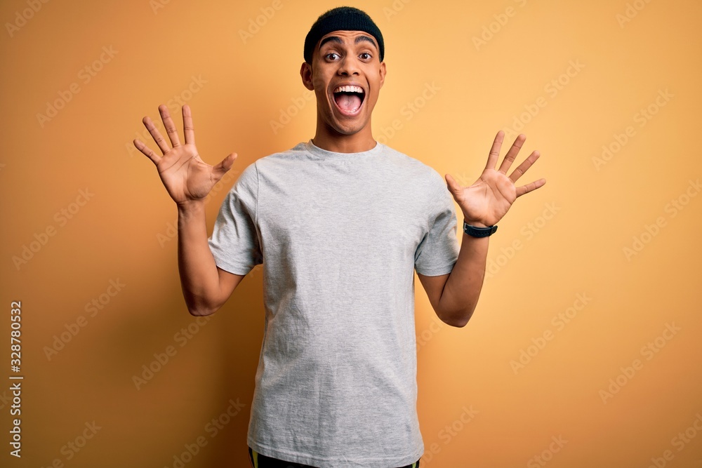 Handsome african american sportsman doing sport wearing sportswear over yellow background celebrating crazy and amazed for success with arms raised and open eyes screaming excited. Winner concept Handsome african american sportsman doing sport wearing sportswear over yellow background celebrating crazy and amazed for success with arms raised and open eyes screaming excited. Winner concept