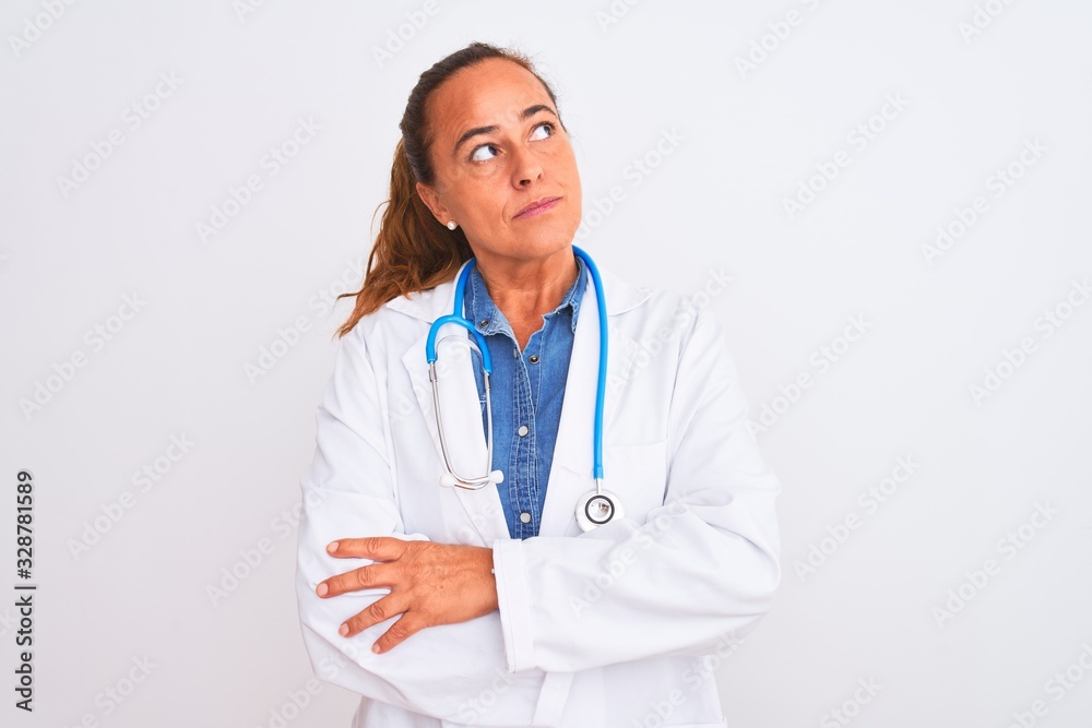 Middle age mature doctor woman wearing stethoscope over isolated background smiling looking to the side and staring away thinking.