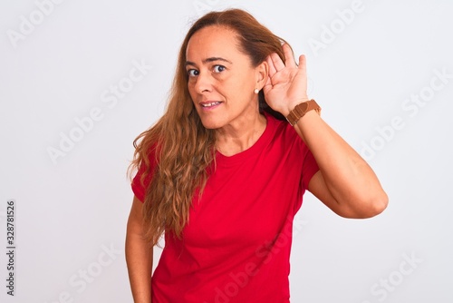 Middle age mature woman standing over white isolated background smiling with hand over ear listening an hearing to rumor or gossip. Deafness concept.