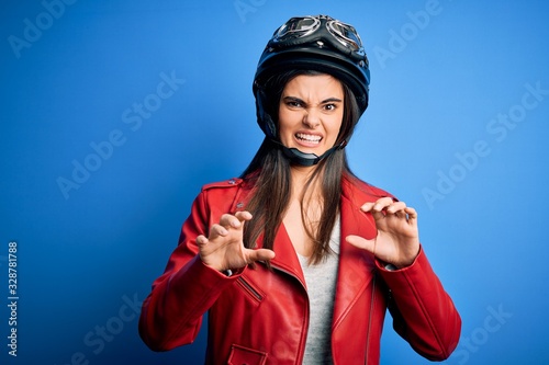 Young beautiful brunette motorcycliste woman wearing motorcycle helmet and jacket disgusted expression, displeased and fearful doing disgust face because aversion reaction. With hands raised © Krakenimages.com