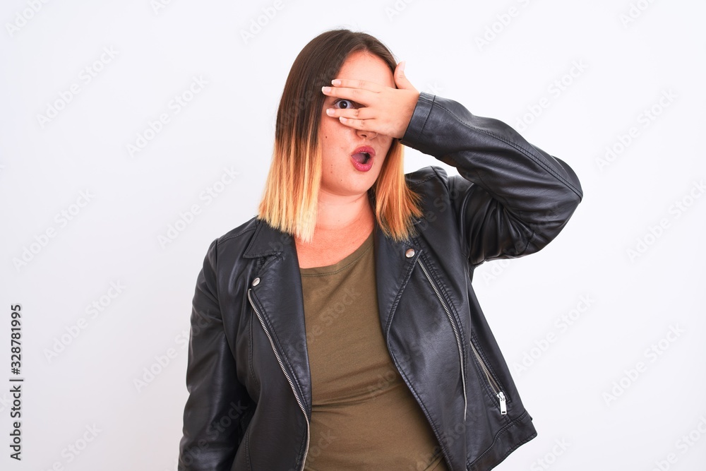 Young beautiful woman wearing t-shirt and jacket standing over isolated white background peeking in shock covering face and eyes with hand, looking through fingers with embarrassed expression. Young beautiful woman wearing t-shirt and jacket standing over isolated white background peeking in shock covering face and eyes with hand, looking through fingers with embarrassed expression.