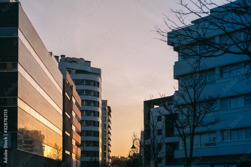 A street of a city with modern buildings entering the sun at sunset reflecting on the crystals