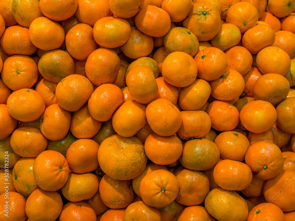 A lot of juicy orange tangerines are piled up