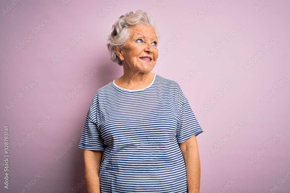 Senior beautiful grey-haired woman wearing casual t-shirt over isolated pink background looking away to side with smile on face, natural expression. Laughing confident. Senior beautiful grey-haired woman wearing casual t-shirt over isolated pink background looking away to side with smile on face, natural expression. Laughing confident.