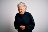 Senior beautiful woman wearing casual black sweater standing over isolated white background with hand on stomach because nausea, painful disease feeling unwell. Ache concept.