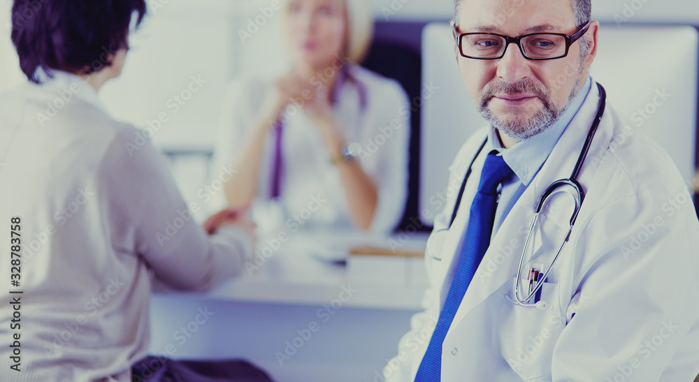 Portrait of senior doctor in office sitting at the desk