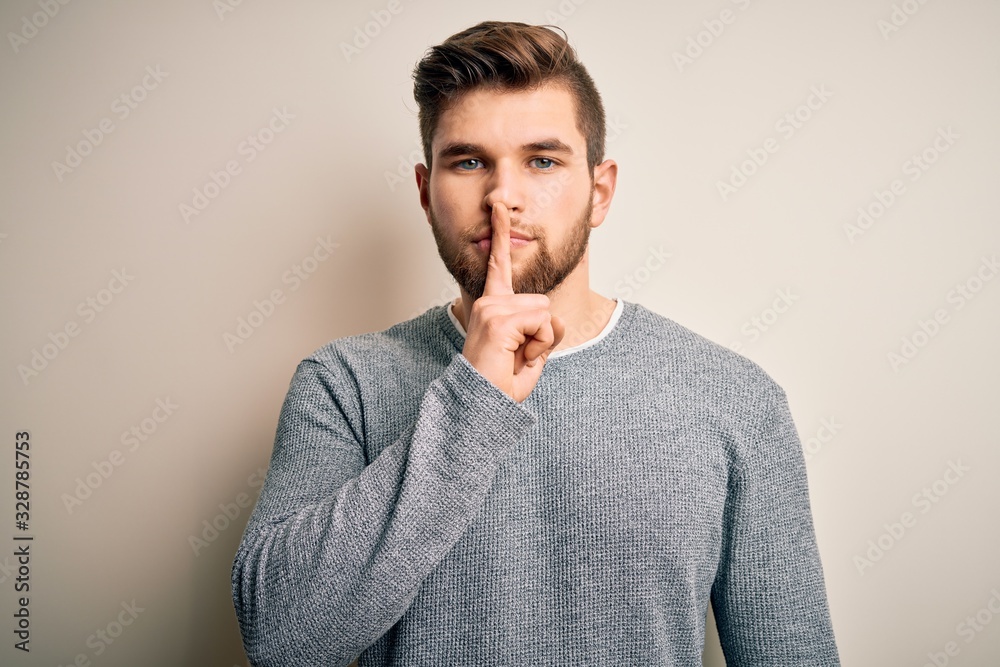 Young handsome blond man with beard and blue eyes wearing casual sweater asking to be quiet with finger on lips. Silence and secret concept. Young handsome blond man with beard and blue eyes wearing casual sweater asking to be quiet with finger on lips. Silence and secret concept.
