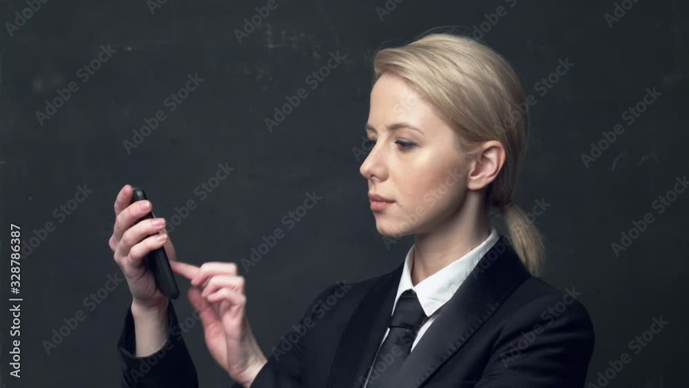 businesswoman in a classic business suit and tie using mobile phone