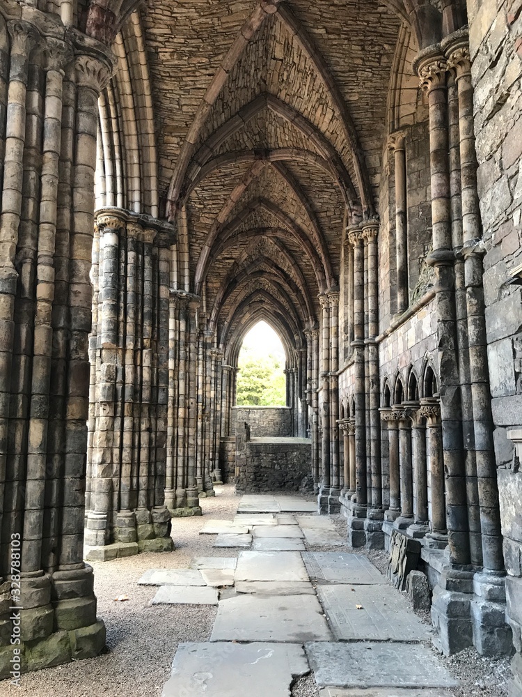 Long arch hallway with stone columns of ancient Holyrood Abbey and Palace Castle in Edinburgh. Home of King James and Mary. Scotland, Great Britain, United Kingdom, Europe.  The Highlander Life.