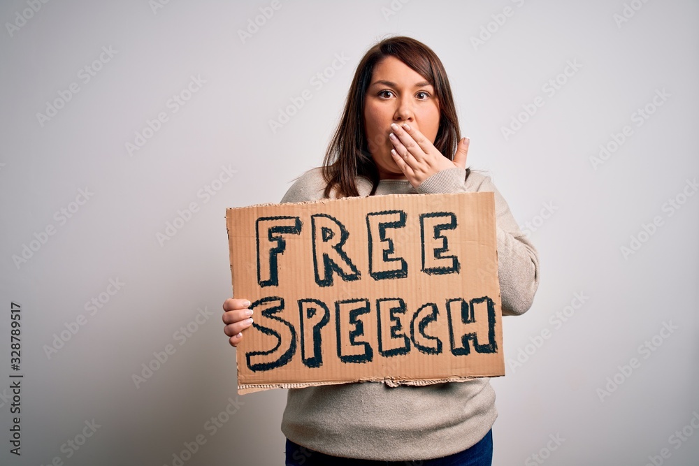 Beautiful plus size woman holding free speech banner for rights protest over isolated background cover mouth with hand shocked with shame for mistake, expression of fear, scared in silence