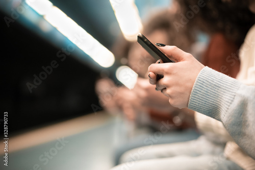 Hand of woman using mobile phones in subway. Girl looking information of the next train on the cellular phone. Concept of people addicted to technology trends. Focus on hand - Image