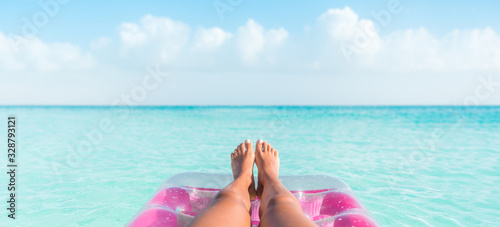 Beach summer vacation woman relaxing on pool float taking feet selfie pov of legs sunbathing relax on pink air mattress inflatable toy floating on blue ocean background panoramic banner. photo