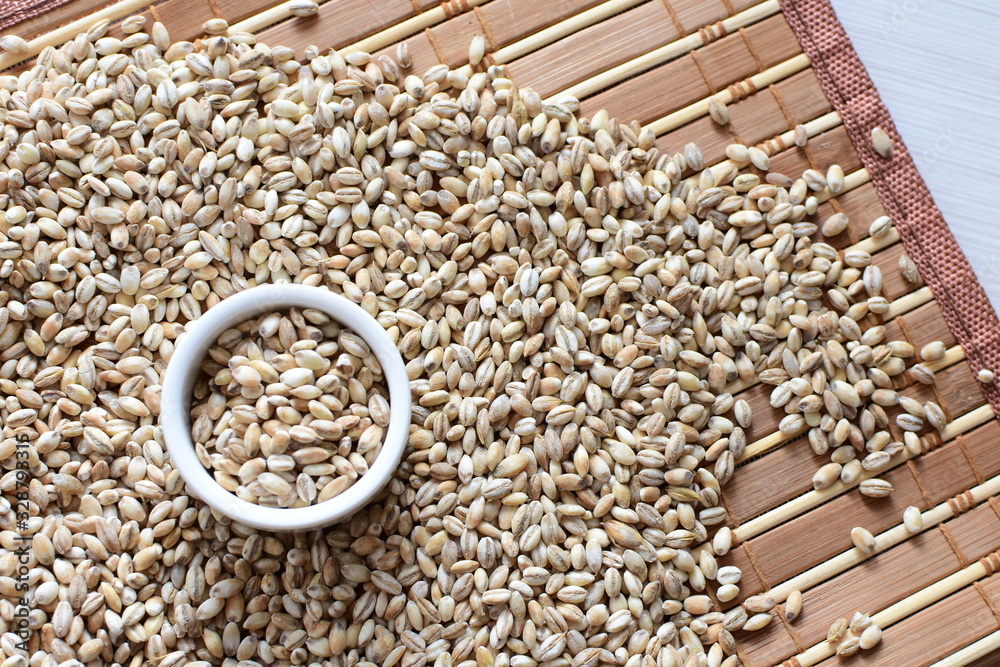 Raw barley grains, displayed in containers on textured background