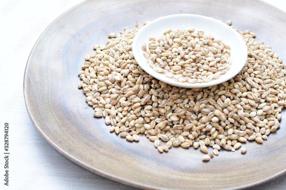 Raw barley grains, displayed in containers on textured background Raw barley grains, displayed in containers on textured background
