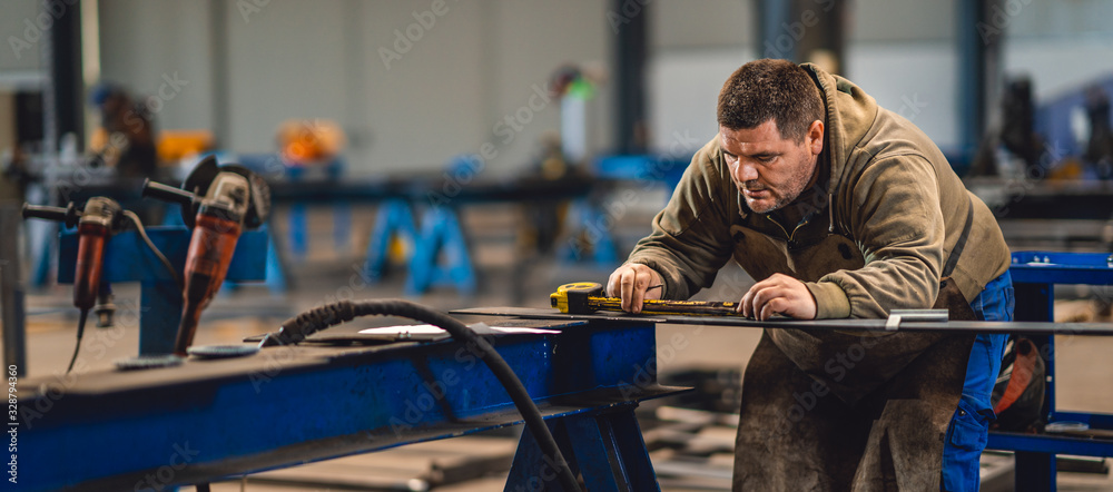 Industrial worker measuring the steel plate - obrazy, fototapety, plakaty 