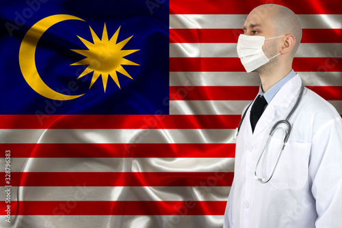 male doctor with a stethoscope on the background of the Malaysia silk national flag, concept of national medical care, health, insurance, tourism